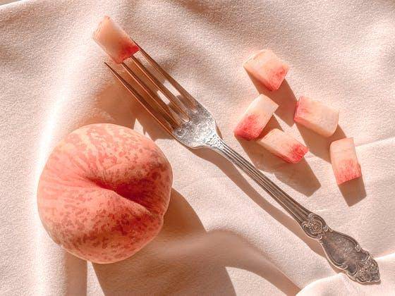 A whole peach on a pink background